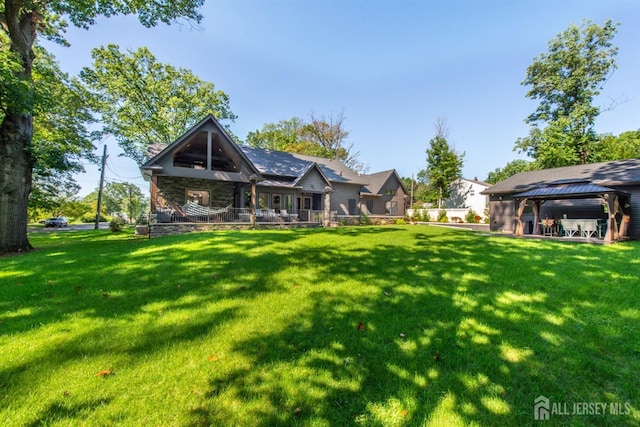 rear view of property featuring a gazebo and a yard