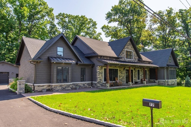 craftsman-style home featuring covered porch, a garage, an outbuilding, and a front lawn