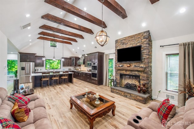 living room featuring high vaulted ceiling, light wood-type flooring, a fireplace, beam ceiling, and a chandelier