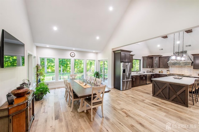 dining space with sink, plenty of natural light, high vaulted ceiling, and light wood-type flooring