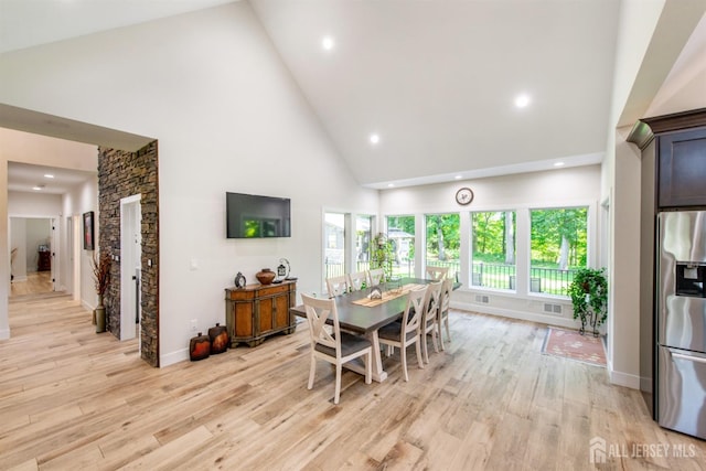 dining space with light wood-type flooring and high vaulted ceiling