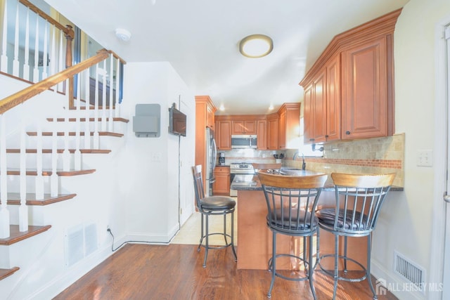 117 Whitman St, Carteret, NJ 07008 - kitchen featuring backsplash, visible vents, appliances with stainless steel finishes, and wood finished floors