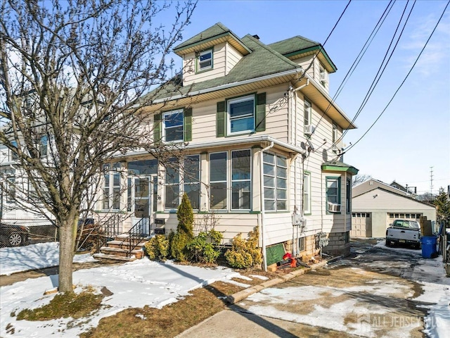 american foursquare style home featuring a garage, cooling unit, and an outbuilding