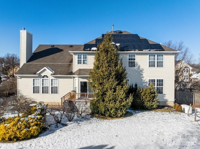 snow covered house featuring solar panels