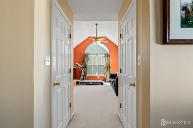 corridor featuring lofted ceiling and light carpet