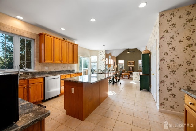 kitchen with pendant lighting, sink, dark stone countertops, a center island, and stainless steel dishwasher