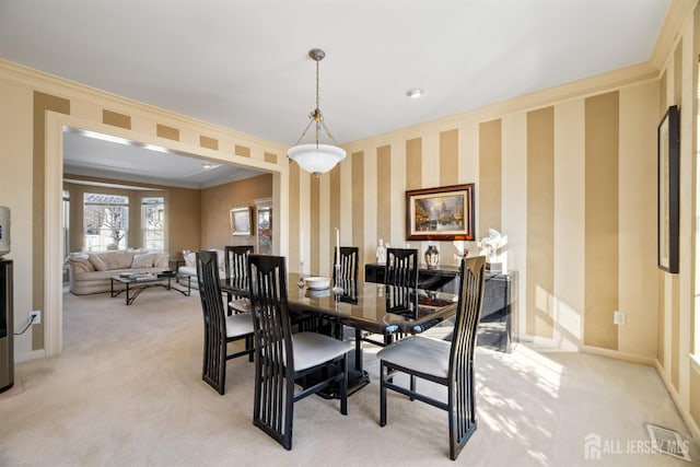 carpeted dining room featuring crown molding