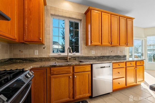 kitchen with sink, decorative backsplash, stainless steel dishwasher, and dark stone counters