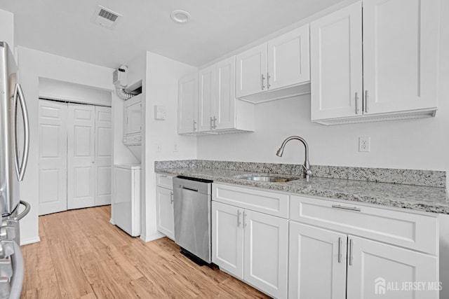 529 Sharon Garden Ct, Woodbridge Proper, NJ 07095 - kitchen featuring stacked washing machine and dryer, appliances with stainless steel finishes, white cabinetry, light wood-type flooring, and light stone countertops