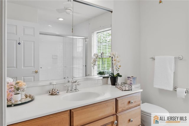 bathroom featuring toilet, a shower with shower door, and vanity