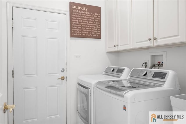 clothes washing area with separate washer and dryer and cabinet space