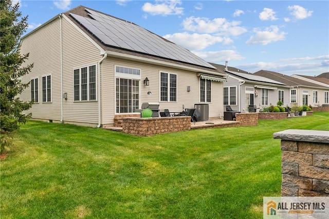 rear view of property featuring a patio, roof mounted solar panels, a yard, and central air condition unit