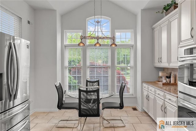 dining room featuring baseboards, vaulted ceiling, light tile patterned floors, and a chandelier