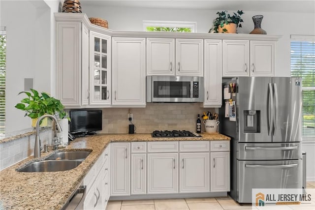 kitchen with appliances with stainless steel finishes, a sink, tasteful backsplash, and plenty of natural light