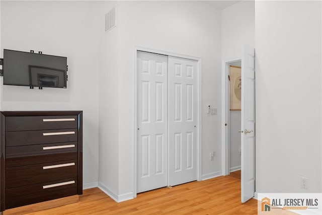 unfurnished bedroom with light wood-style flooring, a closet, and baseboards