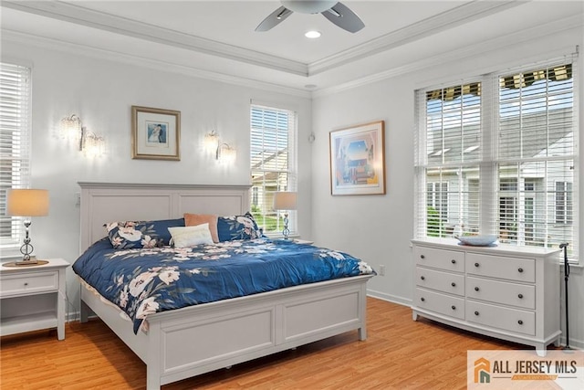 bedroom featuring light wood-style flooring, a raised ceiling, ornamental molding, baseboards, and ceiling fan