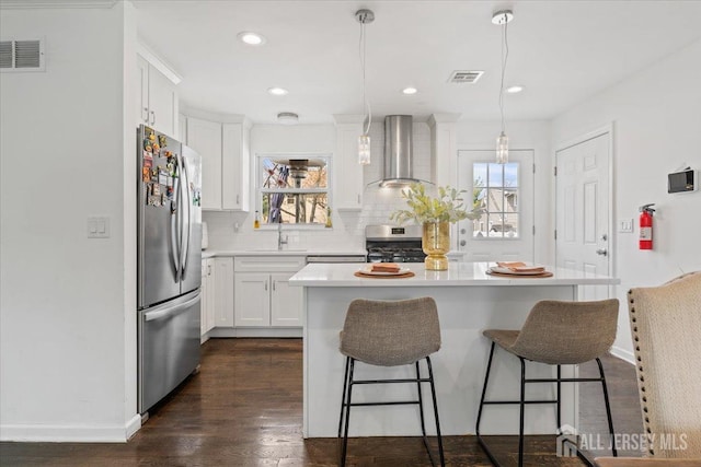 kitchen with visible vents, tasteful backsplash, wall chimney range hood, and stainless steel appliances