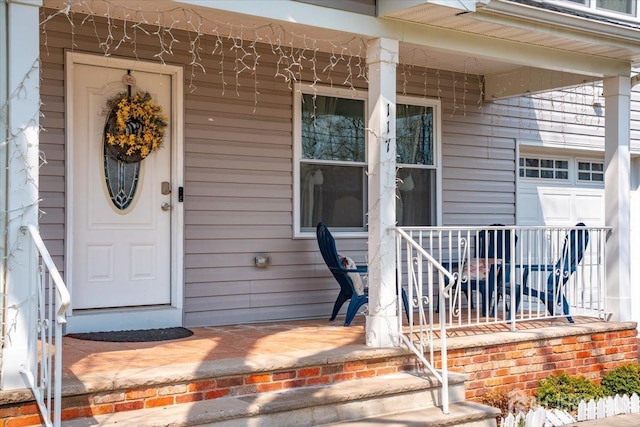 doorway to property with a garage and covered porch