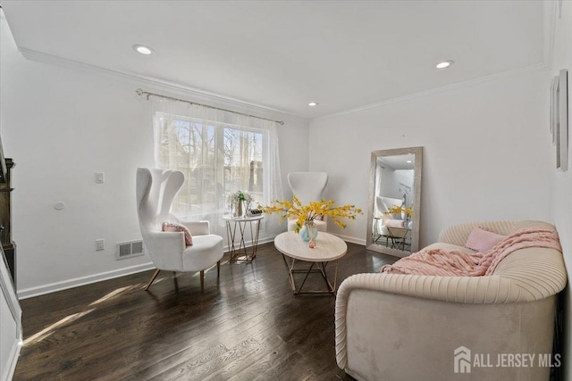 living area with visible vents, ornamental molding, baseboards, and wood finished floors