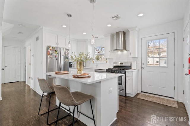 kitchen with visible vents, white cabinetry, wall chimney range hood, and stainless steel appliances