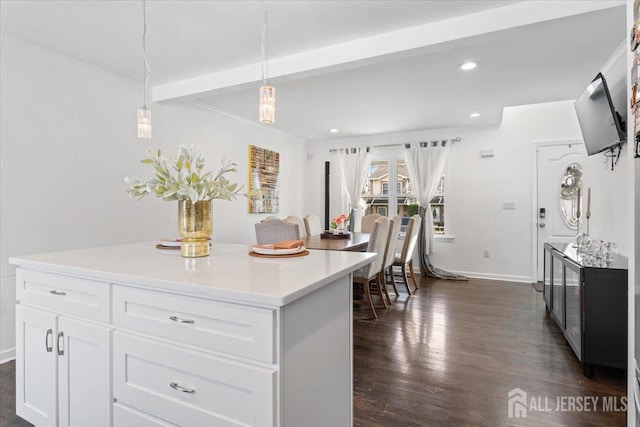 kitchen featuring dark wood-style flooring, pendant lighting, beam ceiling, light countertops, and white cabinets