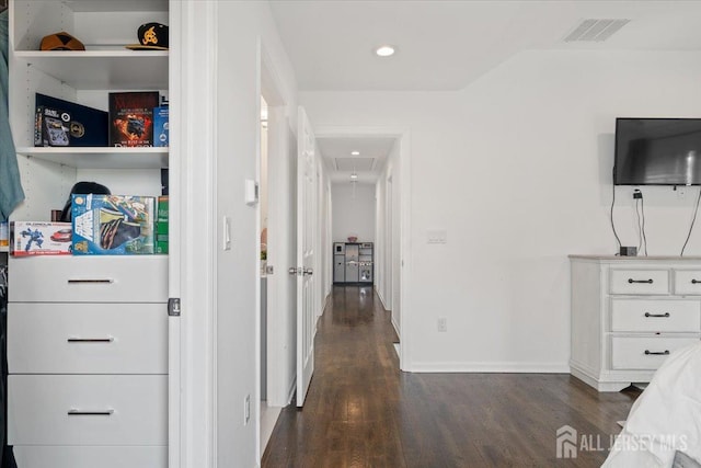 hall with visible vents, attic access, baseboards, and dark wood-style floors