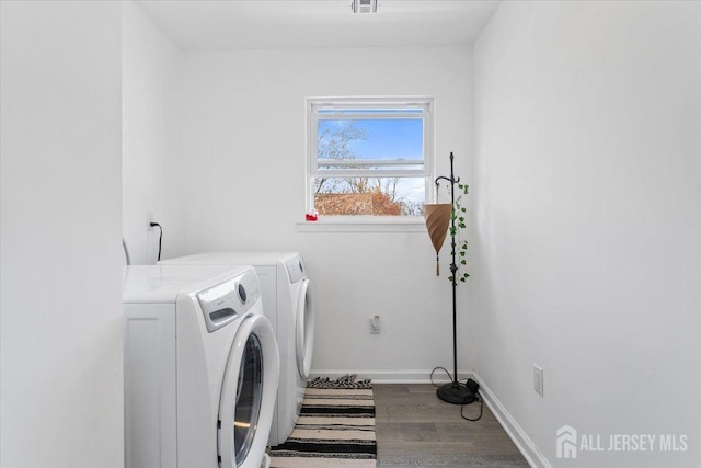 laundry area with laundry area, visible vents, wood finished floors, baseboards, and washer and clothes dryer