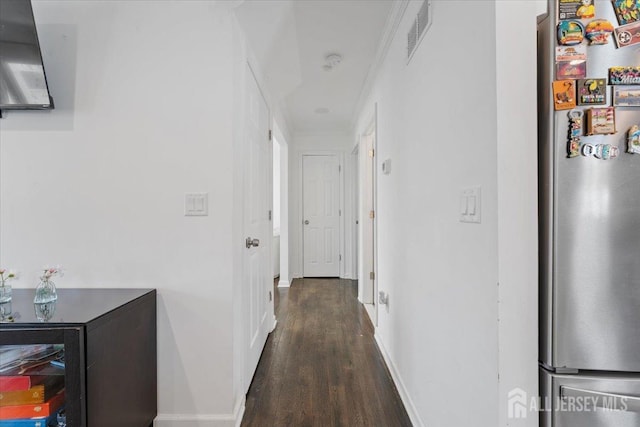 hallway featuring baseboards, visible vents, and wood finished floors