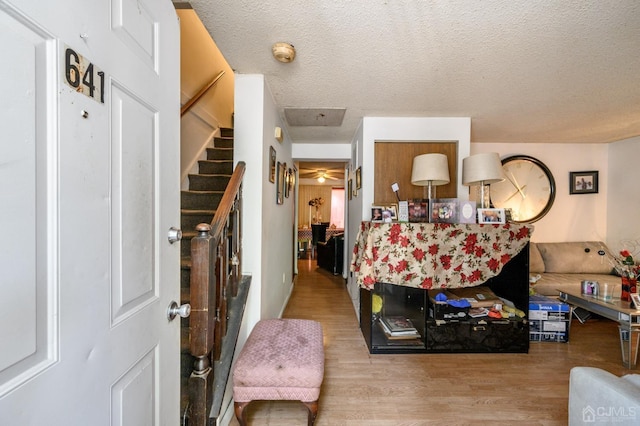 interior space featuring a textured ceiling, wood finished floors, and stairs