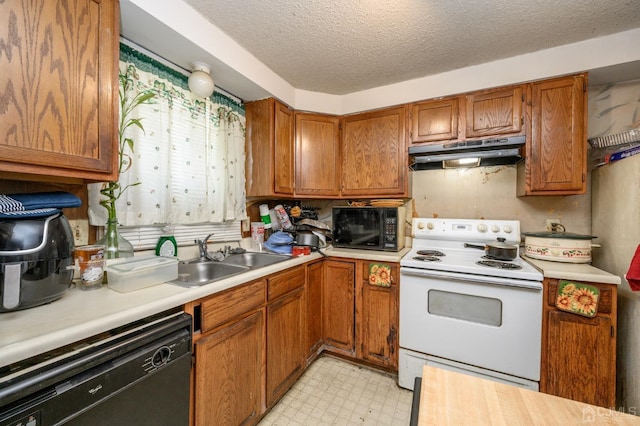 kitchen featuring under cabinet range hood, light floors, brown cabinetry, black appliances, and a sink