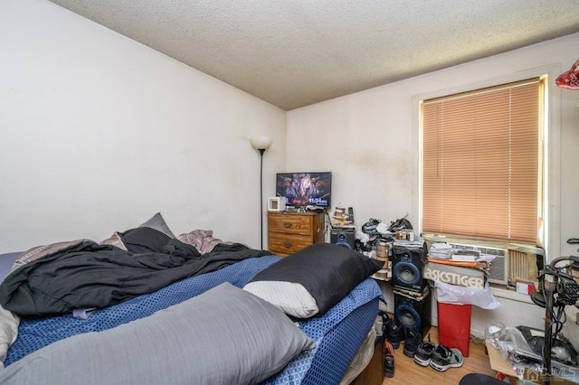 bedroom featuring cooling unit, wood finished floors, and a textured ceiling