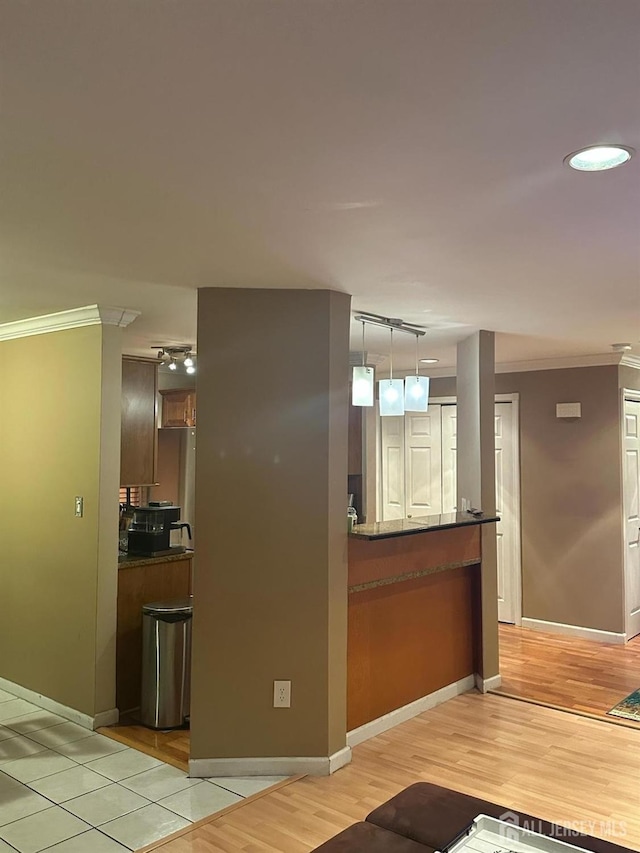 kitchen with track lighting, ornamental molding, light wood-style flooring, and dark countertops