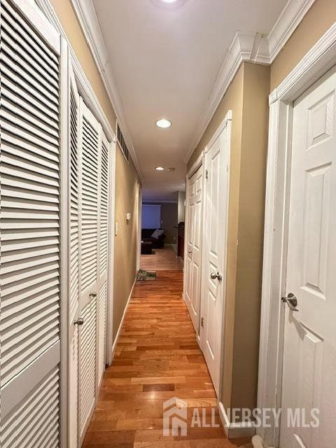corridor featuring recessed lighting, light wood-style floors, and ornamental molding