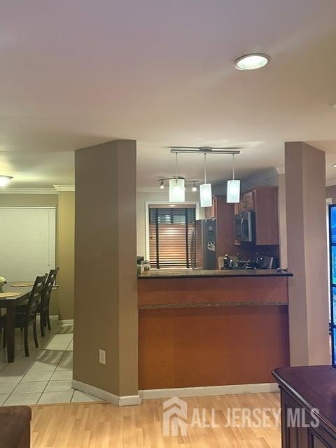 bar area featuring stainless steel microwave, refrigerator, crown molding, pendant lighting, and baseboards