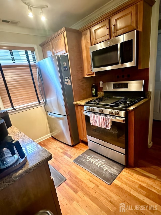 kitchen featuring appliances with stainless steel finishes, light wood finished floors, and ornamental molding