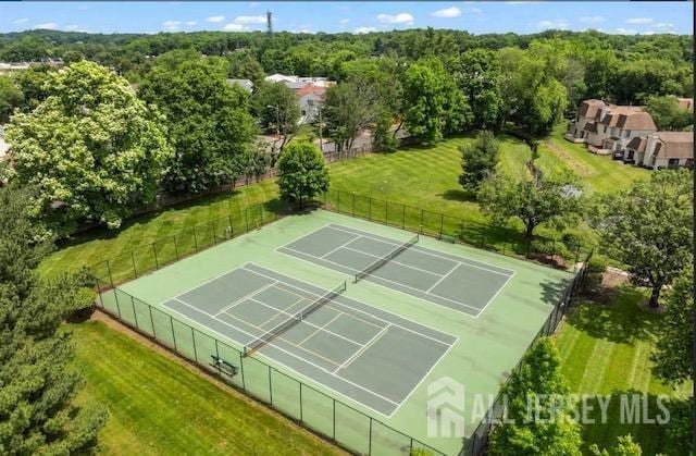view of tennis court with a wooded view