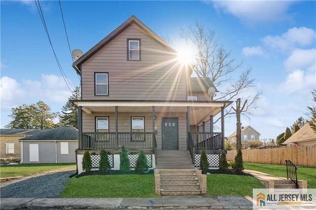 view of front of home with covered porch, fence, and a front yard