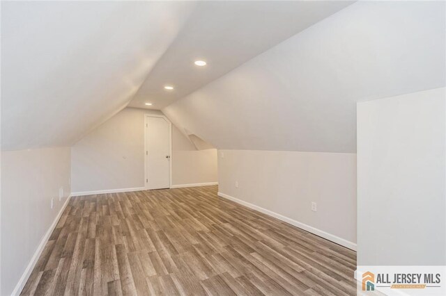 additional living space with lofted ceiling and hardwood / wood-style flooring