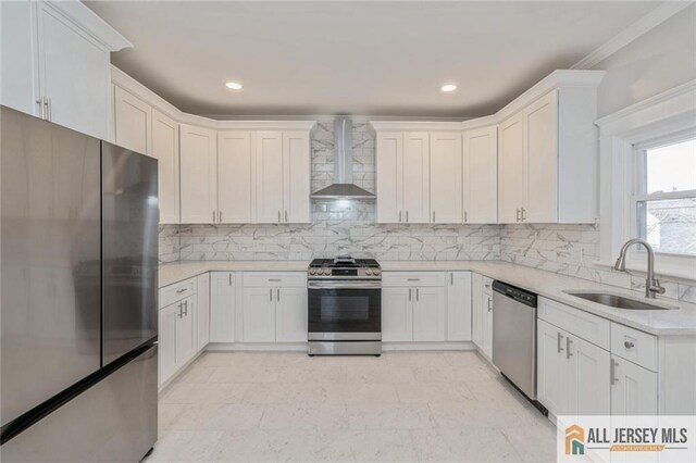 kitchen featuring white cabinetry, appliances with stainless steel finishes, wall chimney range hood, and sink