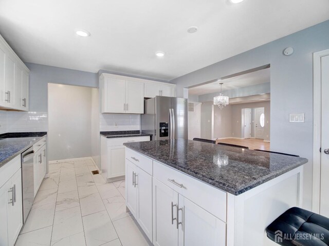 kitchen featuring appliances with stainless steel finishes, a center island, dark stone counters, and white cabinets