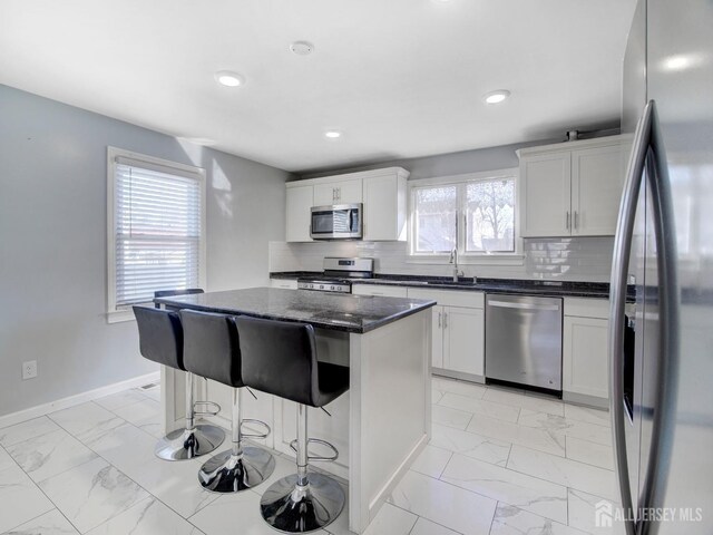 kitchen featuring tasteful backsplash, stainless steel appliances, a center island, and white cabinets