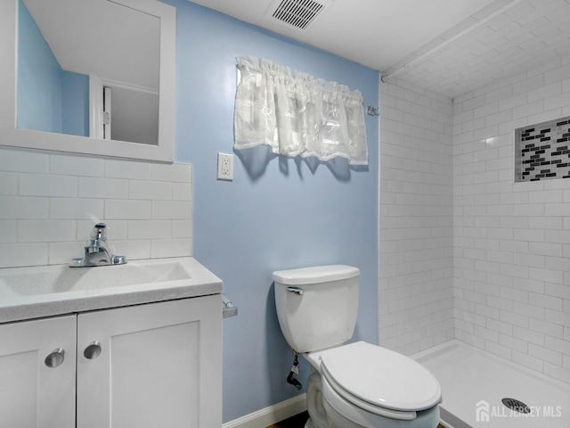 bathroom with tiled shower, vanity, backsplash, and toilet