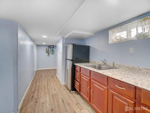 kitchen with sink, light hardwood / wood-style flooring, and stainless steel refrigerator