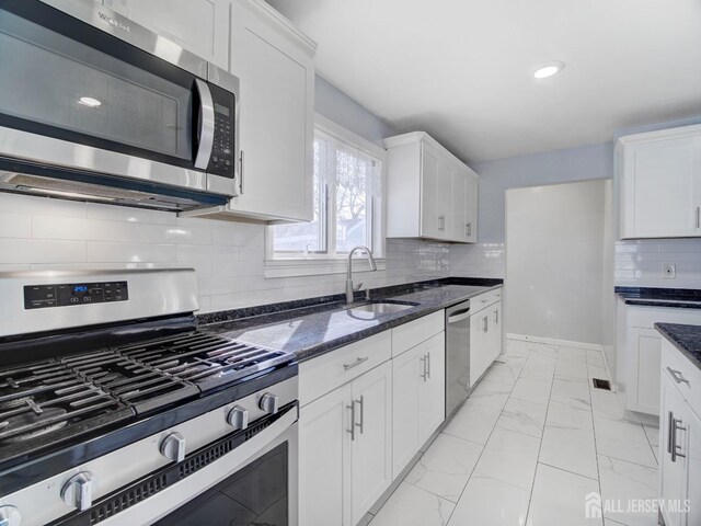 kitchen with white cabinetry, sink, dark stone counters, and appliances with stainless steel finishes