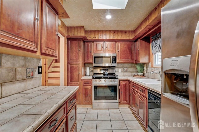 12 Euclid Rd, South Amboy, NJ 08879 - kitchen featuring tile counters, stainless steel appliances, tasteful backsplash, light tile patterned floors, and brown cabinets
