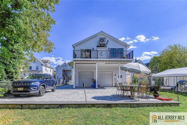 rear view of house with an attached garage, fence, and a patio