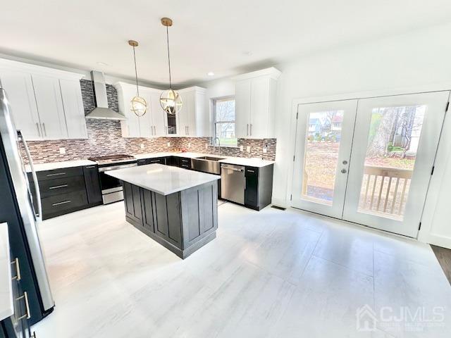 9 Melrose Ave, Sayreville, NJ 08879 - kitchen with white cabinets, backsplash, wall chimney range hood, a kitchen island, and appliances with stainless steel finishes
