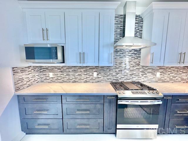 9 Melrose Ave, Sayreville, NJ 08879 - kitchen with stainless steel appliances, light countertops, decorative backsplash, and wall chimney range hood