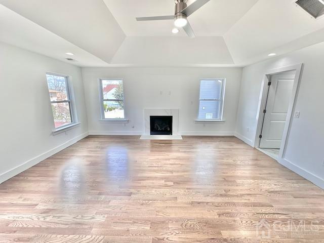 9 Melrose Ave, Sayreville, NJ 08879 - unfurnished living room featuring a raised ceiling, visible vents, a ceiling fan, light wood-style floors, and a premium fireplace
