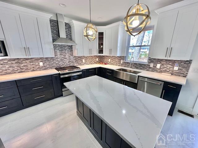 9 Melrose Ave, Sayreville, NJ 08879 - kitchen with a sink, dark cabinetry, stainless steel appliances, wall chimney exhaust hood, and white cabinetry
